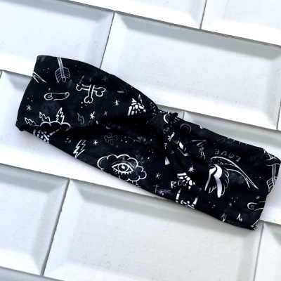 Bandana preta com estampas brancas e nó no centro sobre azulejos brancos