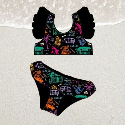 Fato de banho de duas peças colorido sobre areia com padrão de praia e surf.