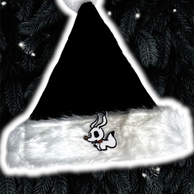 Chapéu de Natal preto e branco com personagem bordado, sobre ramos de pinheiro com luzes