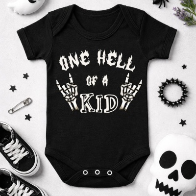 Body bebê preto com texto branco e esqueletos, rodeado de objetos como brinquedos Halloween e ténis