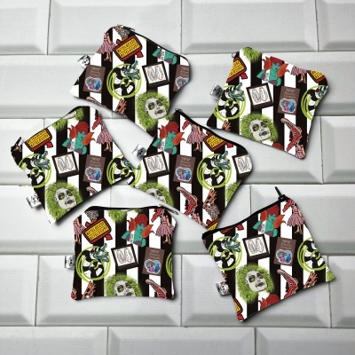 Sete bolsas coloridas de tecido com estampas de bonecos e textos em inglês sobre azulejos brancos