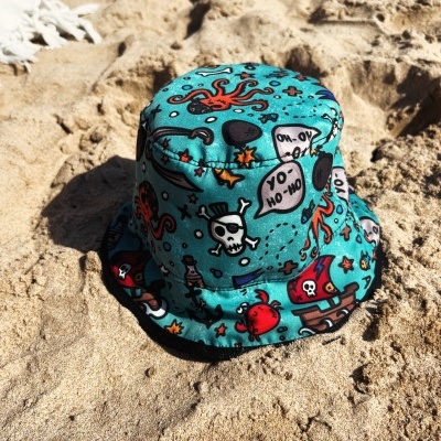 Chapéu tipo pescador colorido com desenhos de pirata na areia da praia