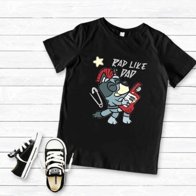 T-shirt preta com desenho e texto ao lado de ténis pretos e brancos sobre madeira clara