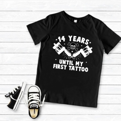 T-shirt preta com estampa branca de tatuagens e texto, com sapatilhas pretas e brancas ao lado