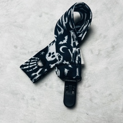 Tira preta com estampas brancas e fivela preta sobre superfície branca peluda