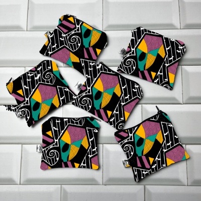 Seis pequenas bolsas de tecido coloridas com padrão geométrico sobre fundo de azulejos brancos