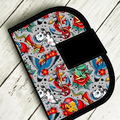 Carteira colorida com desenhos de âncoras, flores, papagaio, peixes e gatos sobre fundo cinza.