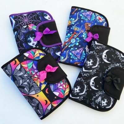 Quatro capas de tecido com estampados coloridos e padrões góticos, com laços decorativos.