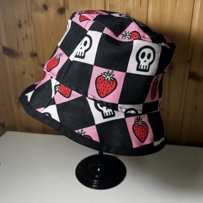 Chapéu de balde com padrão xadrez preto e rosa com morangos e caveiras