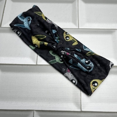 Faixa de cabelo preta com personagens cartoon coloridos sobre azulejos brancos