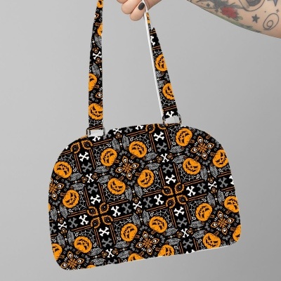 Mala com padrão de Halloween segurada por uma mão tatuada