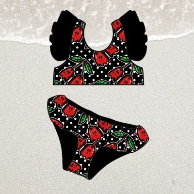 Biquíni duas peças com padrão floral vermelho e pontos brancos sobre preto na areia