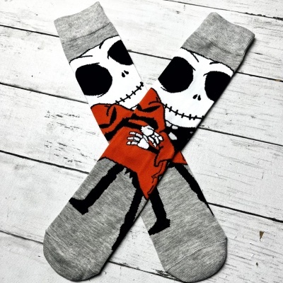 Meias cinzentas com esqueleto estampado com casaco vermelho sobre fundo de madeira