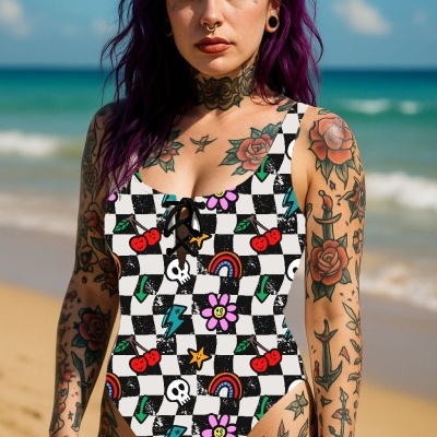 Fato de banho com padrão colorido de desenhos e azulejos em preto e branco usado por mulher tatuada na praia