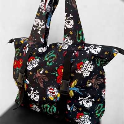 Mala de ombro preta com estampado colorido de caveiras, corações, águias e cobras