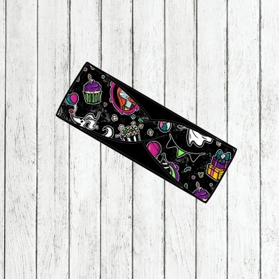 Faixa preta com desenhos coloridos festivos sobre fundo de madeira branca desgastada.