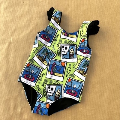 Fato de banho infantil colorido com padrões de esqueletos e palmeiras