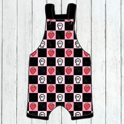 Jardineira infantil com padrão de quadrados rosa e preto, morangos e caveiras