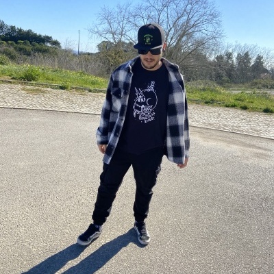 Homem com boné preto e camisa xadrez preta e branca ao ar livre