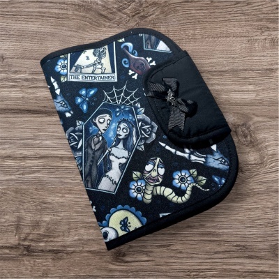 Estojo com padrão de desenho animado e laço preto sobre mesa de madeira