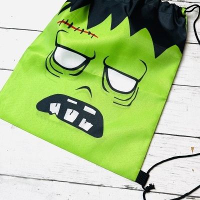 Mochila saco verde com estampa de rosto de monstro e cordões pretos