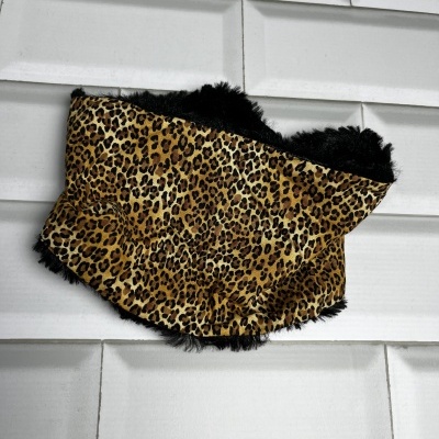 Cachecol com padrão de pele de leopardo e interior peludo preto sobre fundo de azulejos brancos