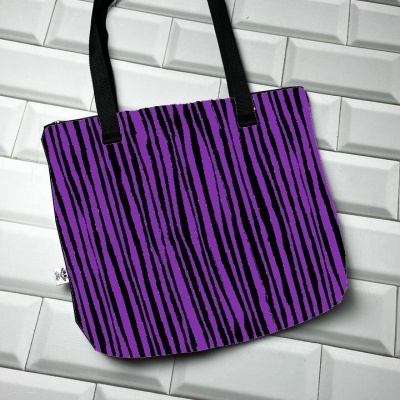 Saco roxo com riscas pretas e alças pretas sobre azulejos brancos.