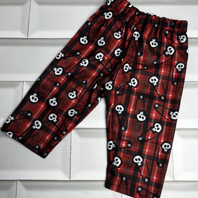 Calças com padrão xadrez vermelho e preto com caveiras brancas