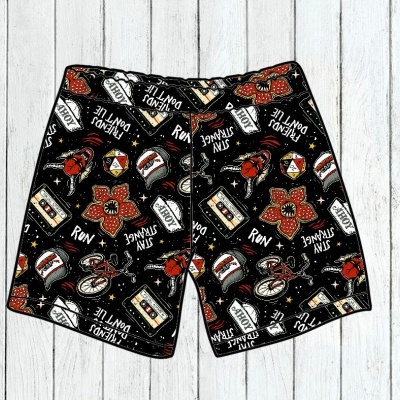 Calções pretos com padrão colorido e texto em inglês sobre fundo de madeira clara