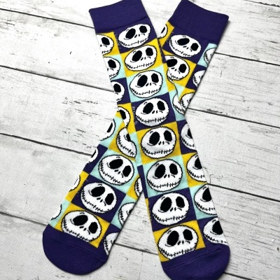 Meias compridas coloridas com padrão de caras de caveira em fundo xadrez colorido.