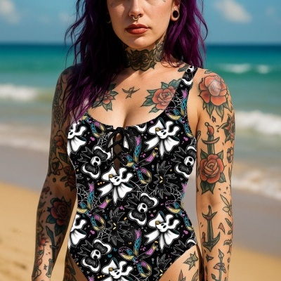 Fato de banho preto com padrão de fantasmas e flores coloridas usado por mulher tatuada numa praia