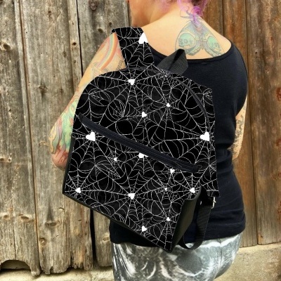 Mochila preta com padrão de teias de aranha e estrelas brancas usada por pessoa com tatuagens