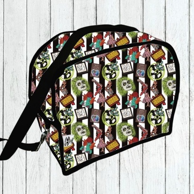 Bolsa colorida com padronagem e alça preta sobre fundo de madeira branca