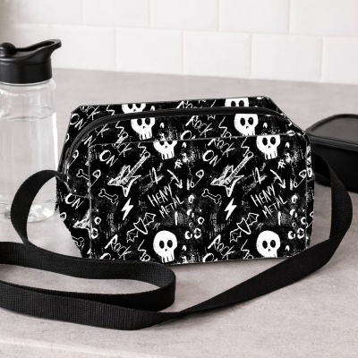 Bolsa preta com padrão de caveiras brancas e palavras Rock e Heavy Metal colocada sobre bancada cinza.