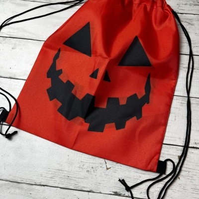 Mochila vermelha com estampa de abóbora preta e cordões pretos