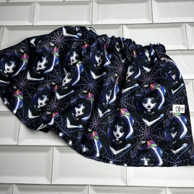 Pano com padrão repetido de personagens femininas em fundo preto com teias de aranha, tecido elástico