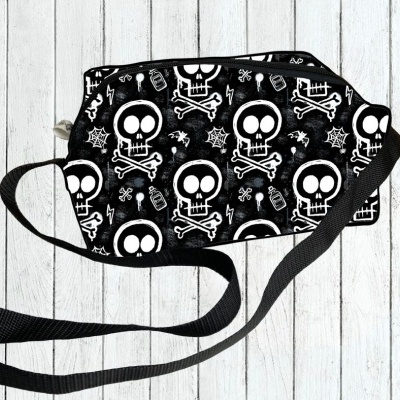 Mala preta com padrão de caveiras brancas e ossos cruzados