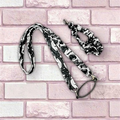 Estojo porta óculos e porta chaves com padrão preto e branco sobre fundo de tijolos rosa