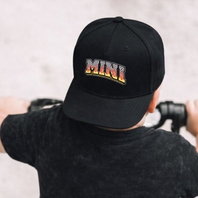 Boné preto com texto MINI visto de trás numa criança com camiseta preta.