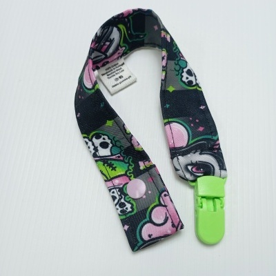 Prendedor de chupeta com padrão colorido e clip verde.