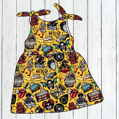 Vestido infantil colorido com padrão de desenhos e texto, sobre fundo amarelo.