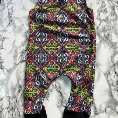 Macacão de criança com padrão colorido e caveiras sobre superfície branca de mármore