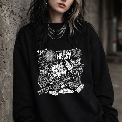 Mulher com sweatshirt preta estampada com texto e desenhos brancos, cabelo preto e loiro