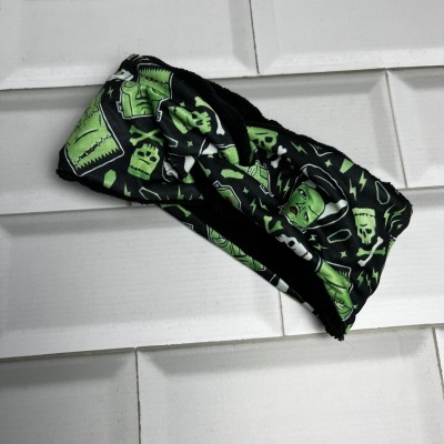 Faixa de cabeça preta com padrão verde de Frankenstein e caveiras colocada sobre azulejos brancos