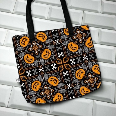 Sacola preta com padrão de abóboras laranja e caveiras brancas
