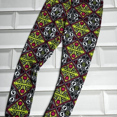Lenço ou faixa de tecido colorida com padrão de caveiras e desenhos geométricos.