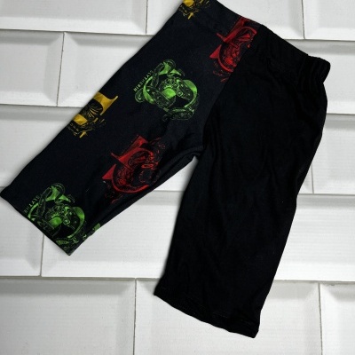 Calções pretos com padrão colorido numa perna sobre azulejos brancos