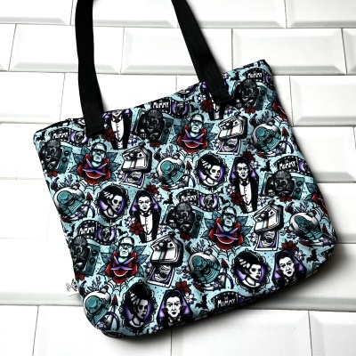 Mala tote com padrão de monstros clássicos de filmes de terror, fundo branco e alças pretas