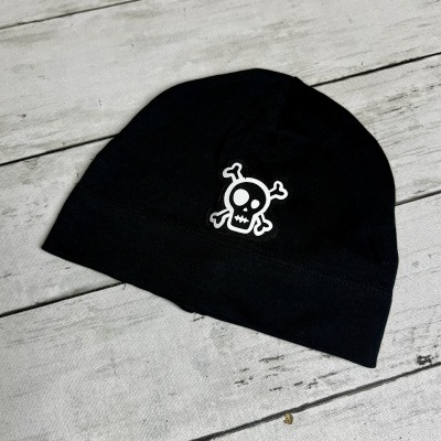 Gorro preto com estampa de caveira branca sobre fundo de madeira clara.