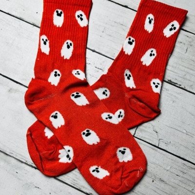 meias vermelhas com fantasmas brancos e olhos pretos sobre chão de madeira branca